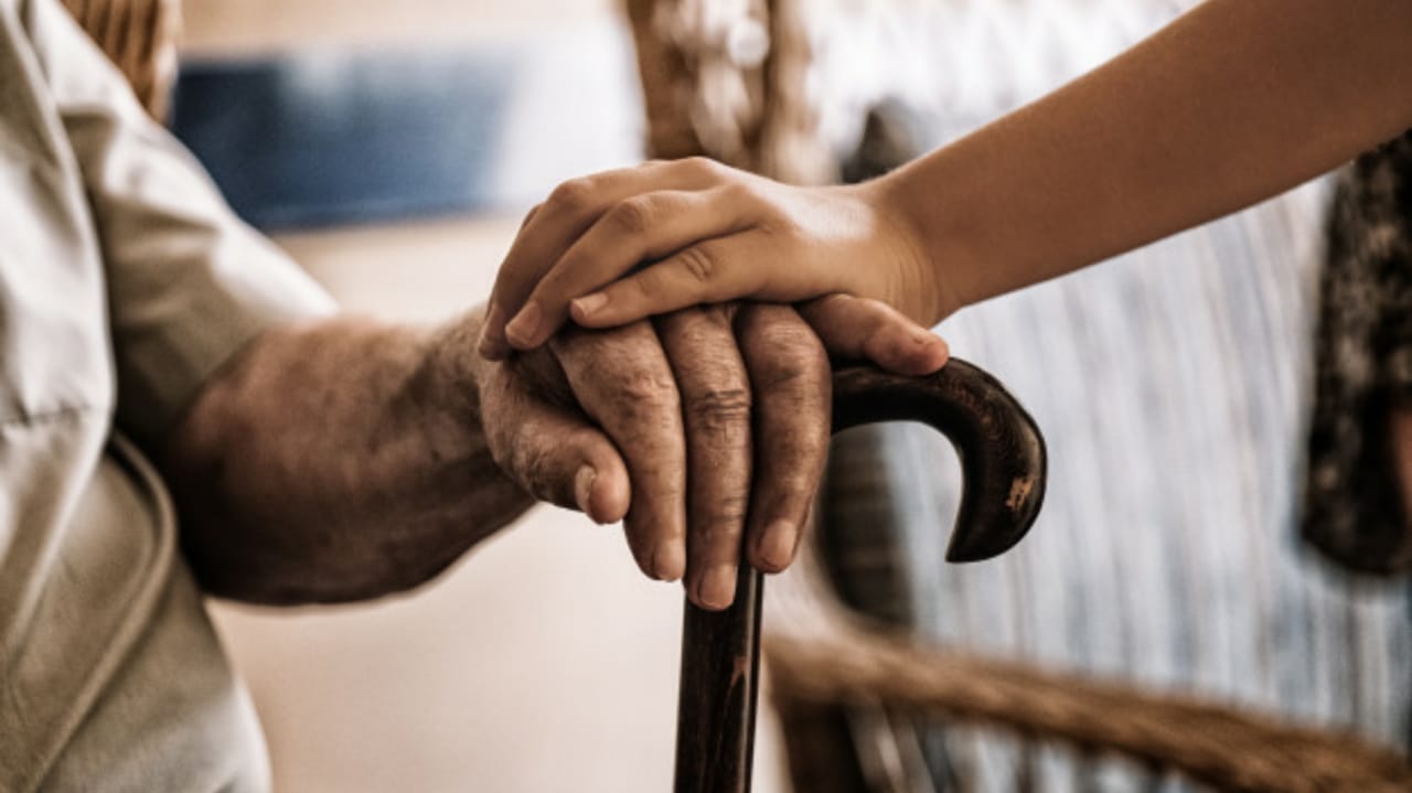 Pessoa segurando a mão de um idoso