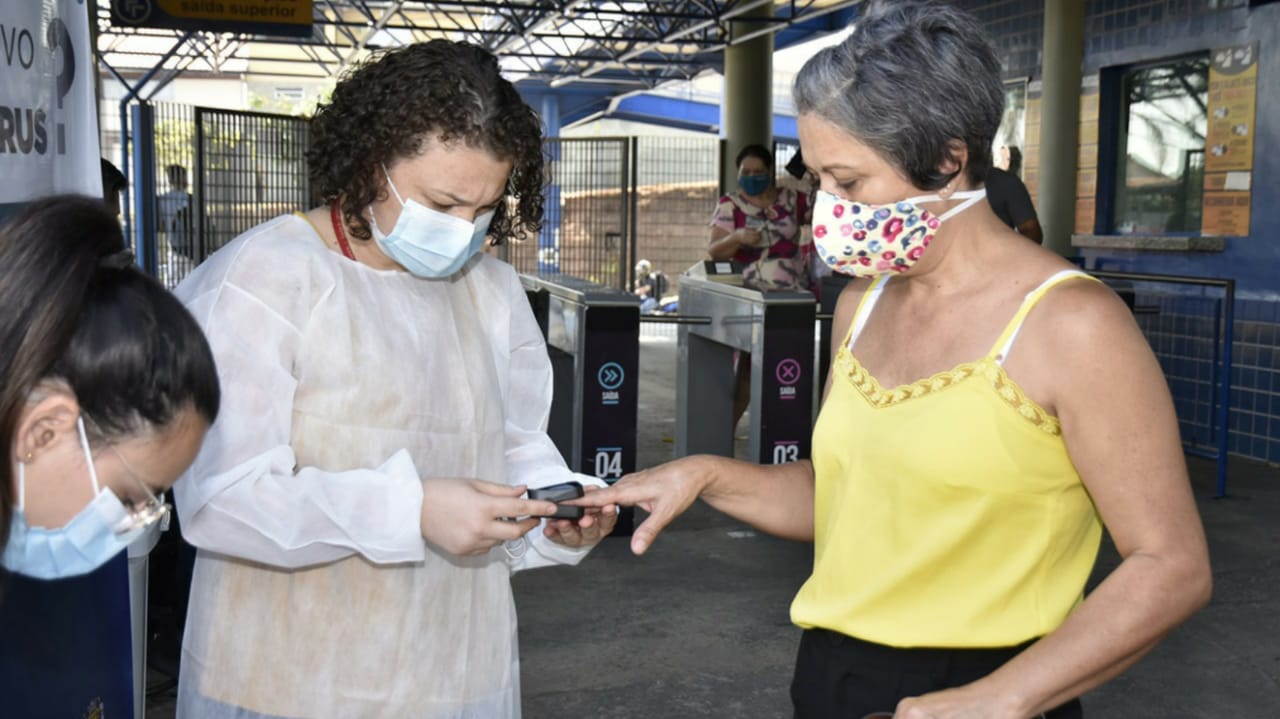 Profissional realizando teste de Covid-19 em mulher no terminal Eloy Chaves