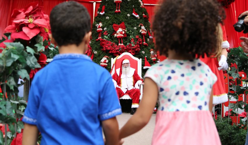 Crianças em frente ao Papai Noel em decoração natalina