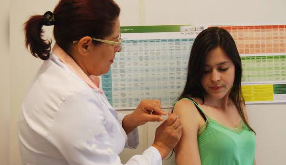 Profissional da saúde aplicando vacina em mulher
