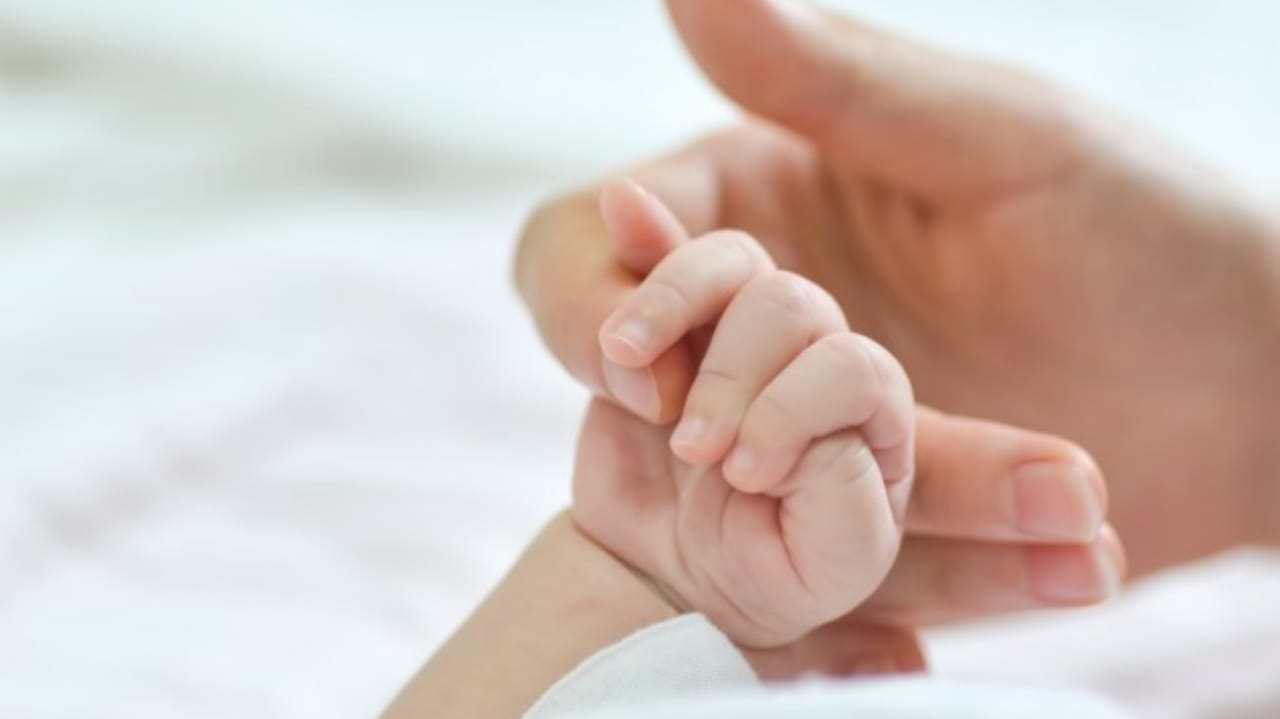Mulher segurando mão de bebê