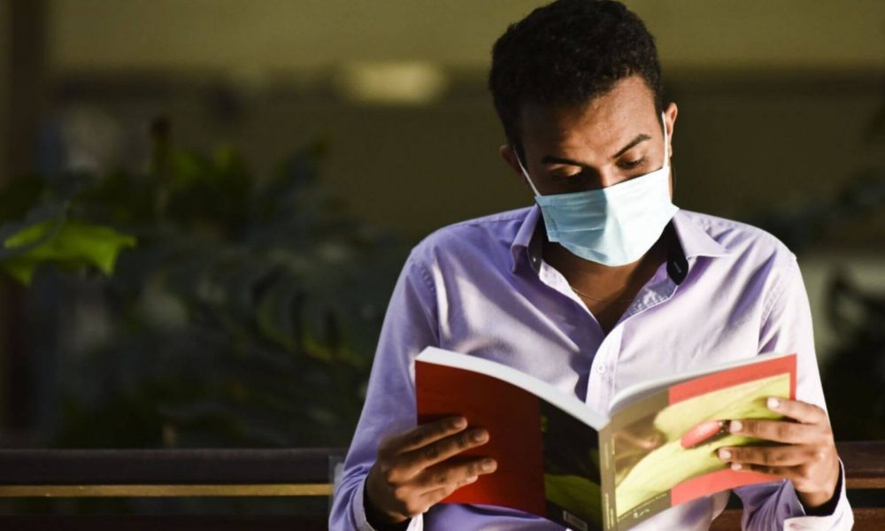 Homem usando máscara lendo um livro