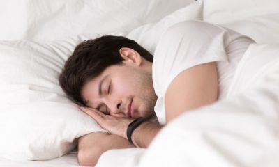 Homem dormindo em cama com travesseiros brancos