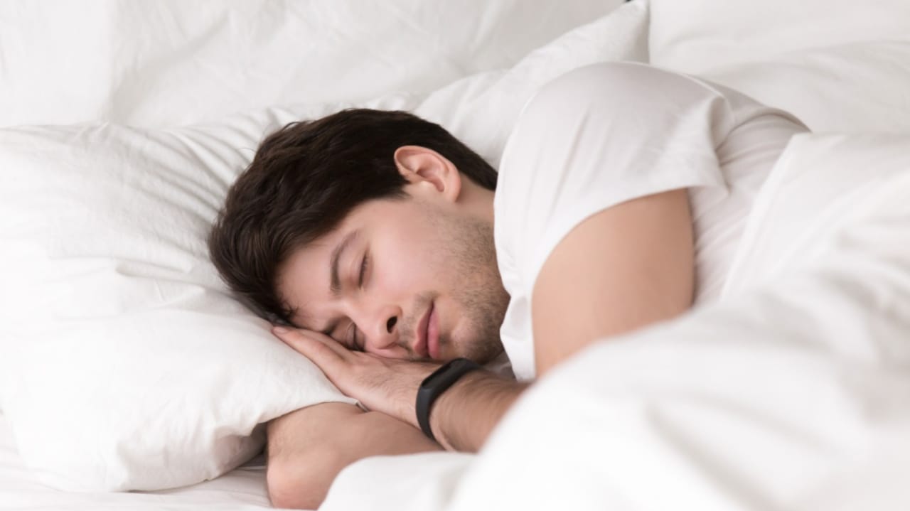 Homem dormindo em cama com travesseiros brancos