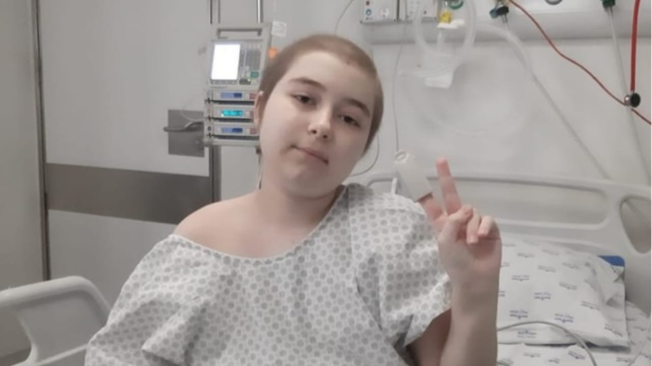 Menina sentada em leito de hospital