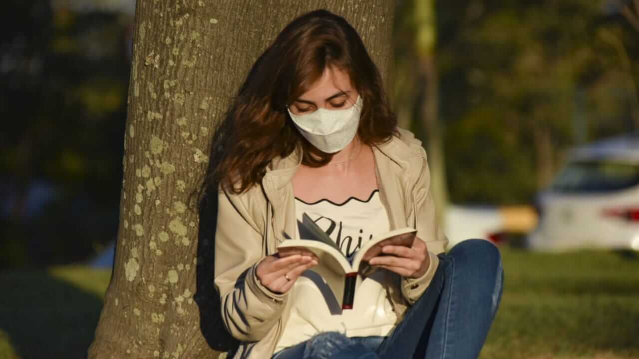 Mulher lendo um livro embaixo de uma árvore