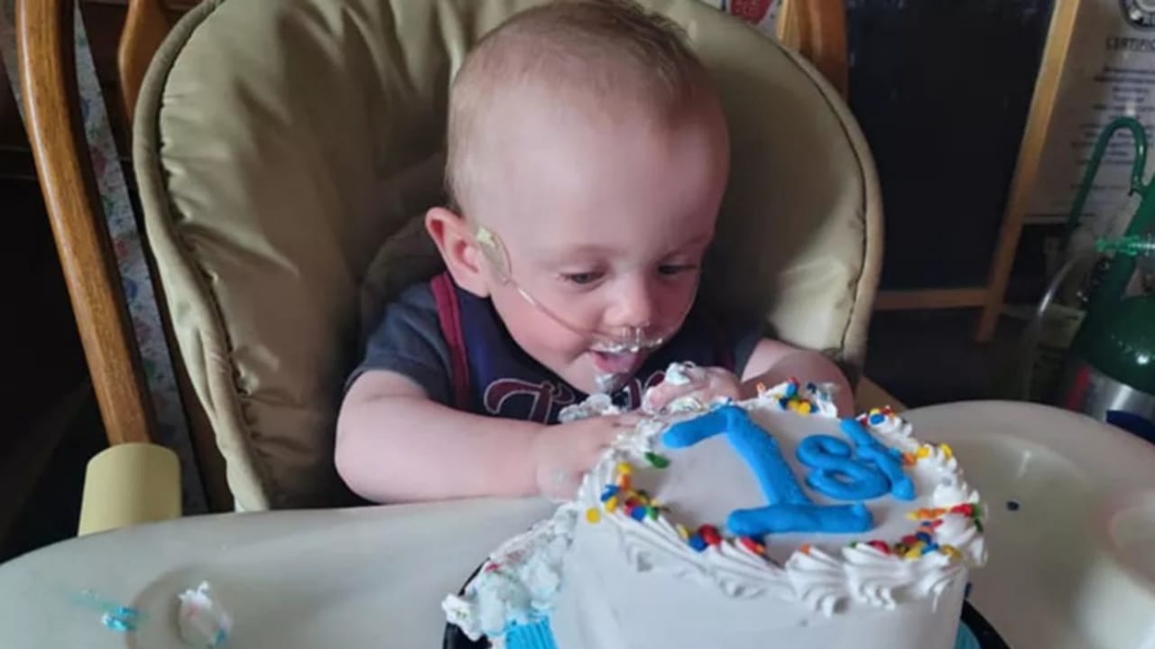 Bebê em frente a bolo de aniversário