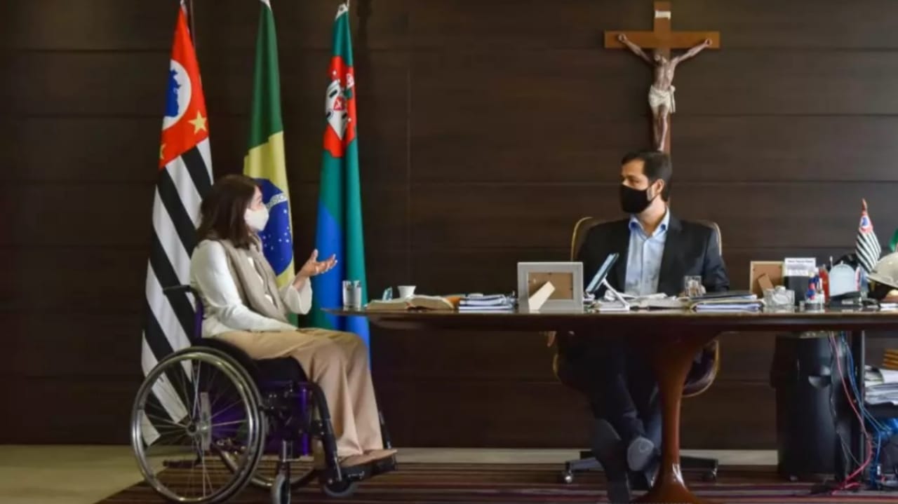 Célia Leão em cadeira de rodas conversando com prefeito Luiz Fernando