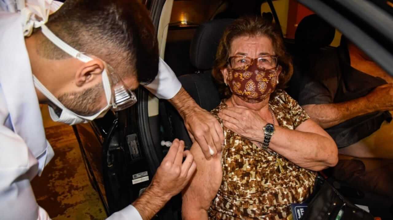 Idosa sendo vacinada contra gripe dentro de carro em Jundiaí