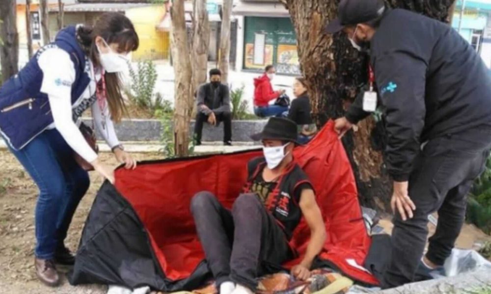 Voluntários de projeto social doando saco de dormir para homem em situação de rua