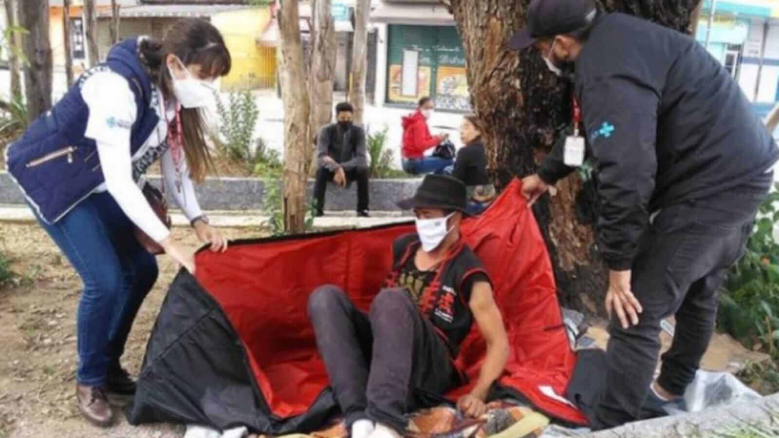 Voluntários de projeto social doando saco de dormir para homem em situação de rua