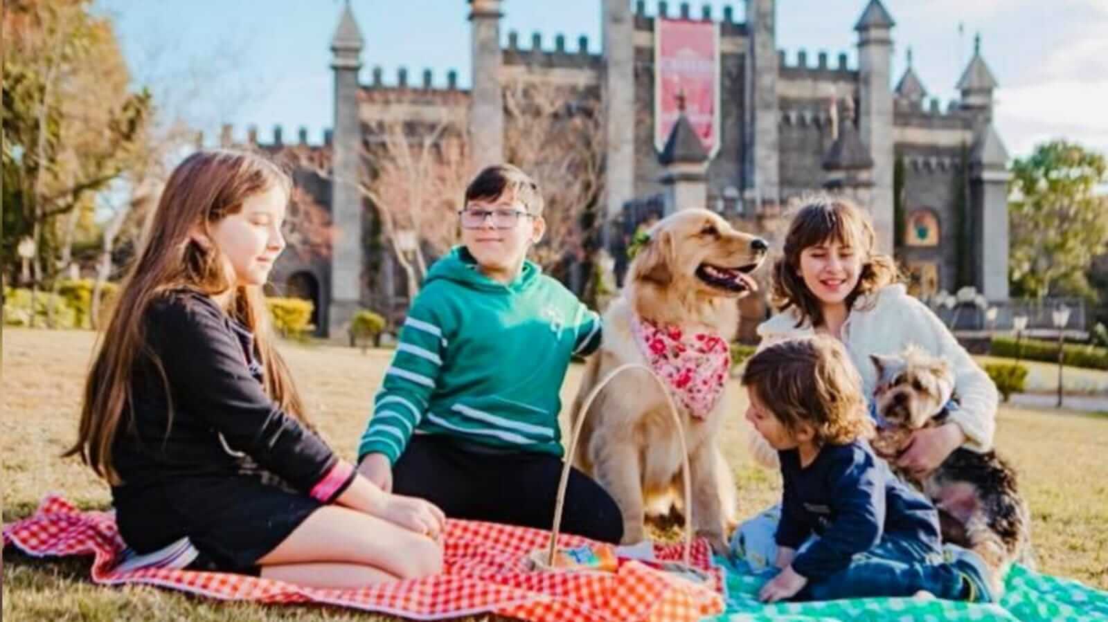 Crianças e cachorro em piquenique em frente a Castelo