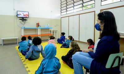 Crianças e professora em sala de aula assistindo vídeo em TV