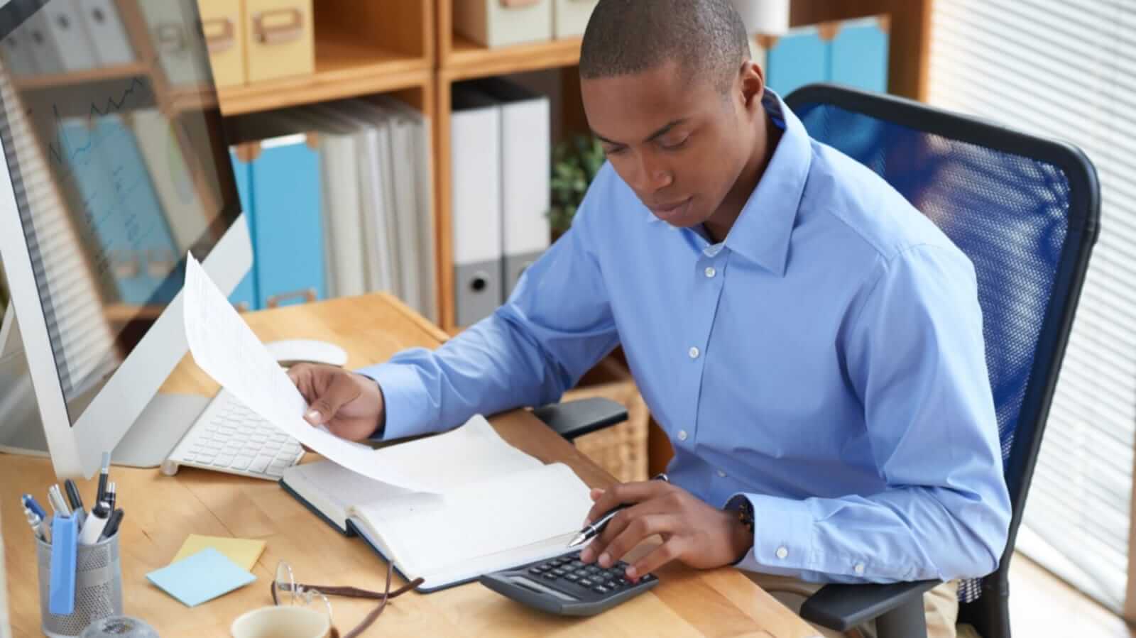 Homem em escritório com papéis e calculadora