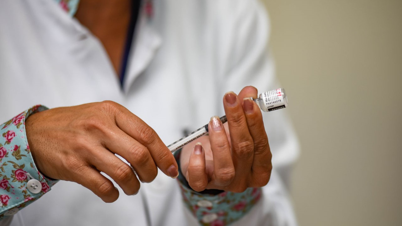Homem segurando seringa de vacina