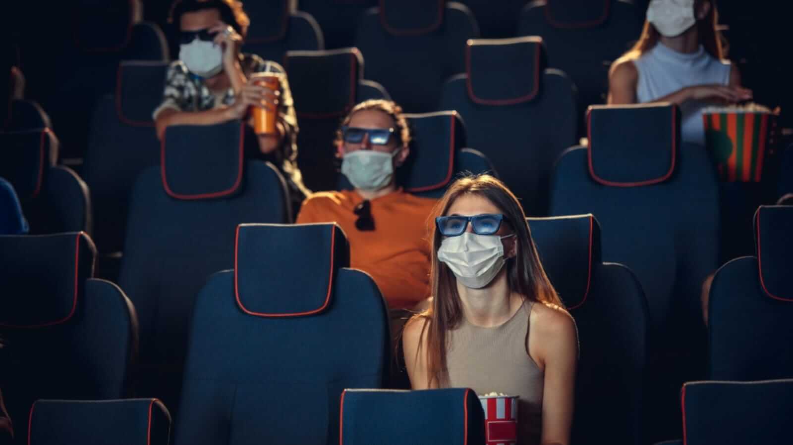 Pessoas de máscara em sala de cinema