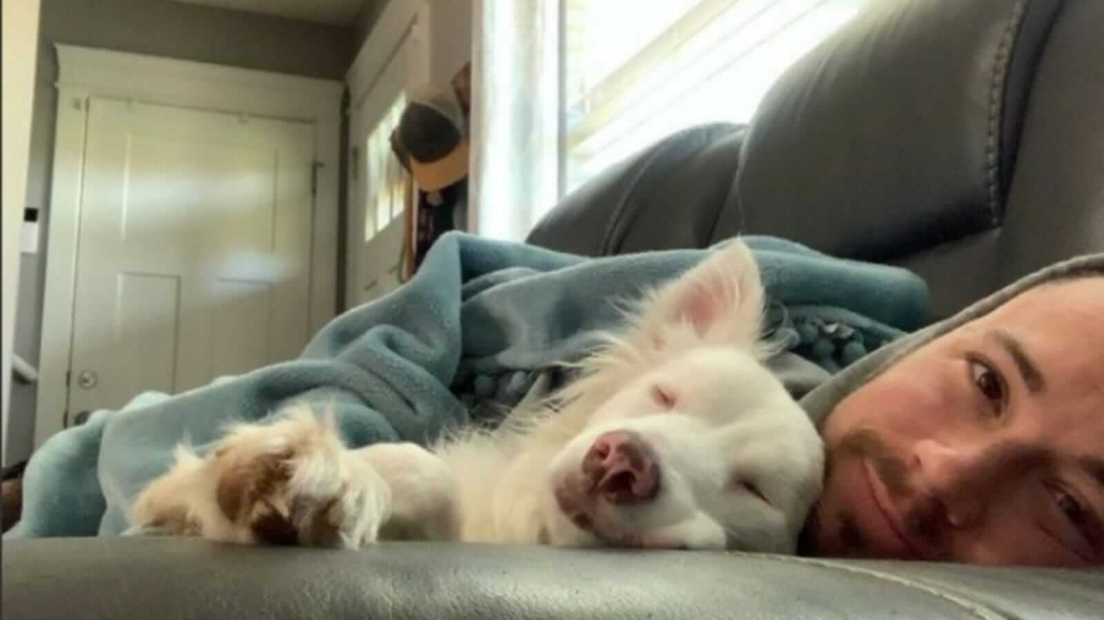Homem e cachorro deitados em sofá