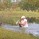 Homem em lago salvando cachorro de jacaré