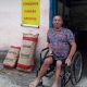 Homem de cadeira de rodas em frente à casa rosa