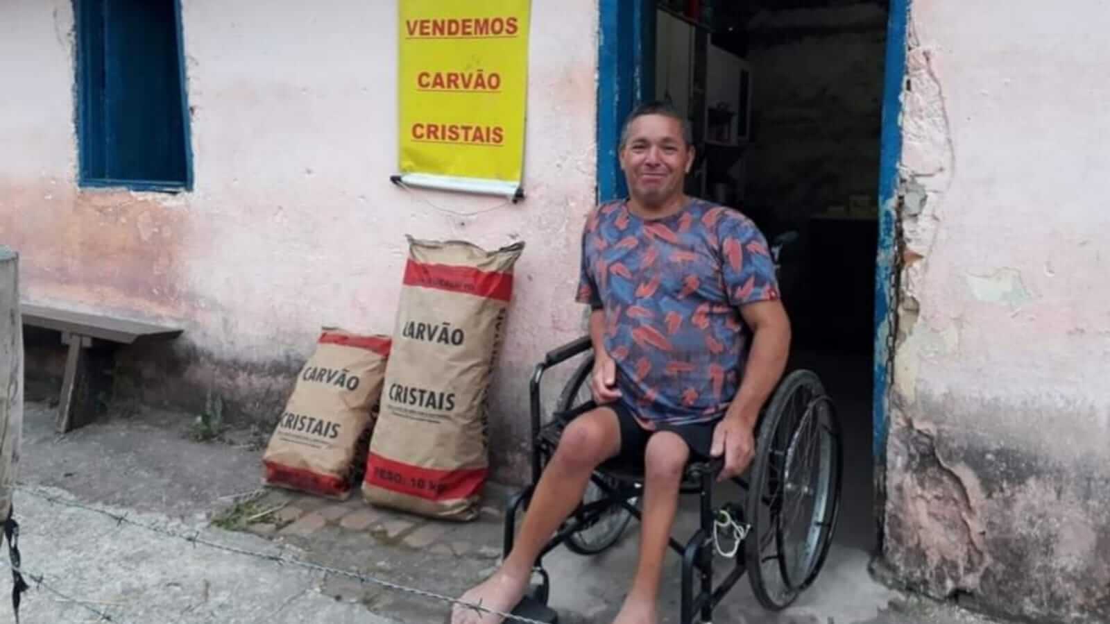 Homem de cadeira de rodas em frente à casa rosa