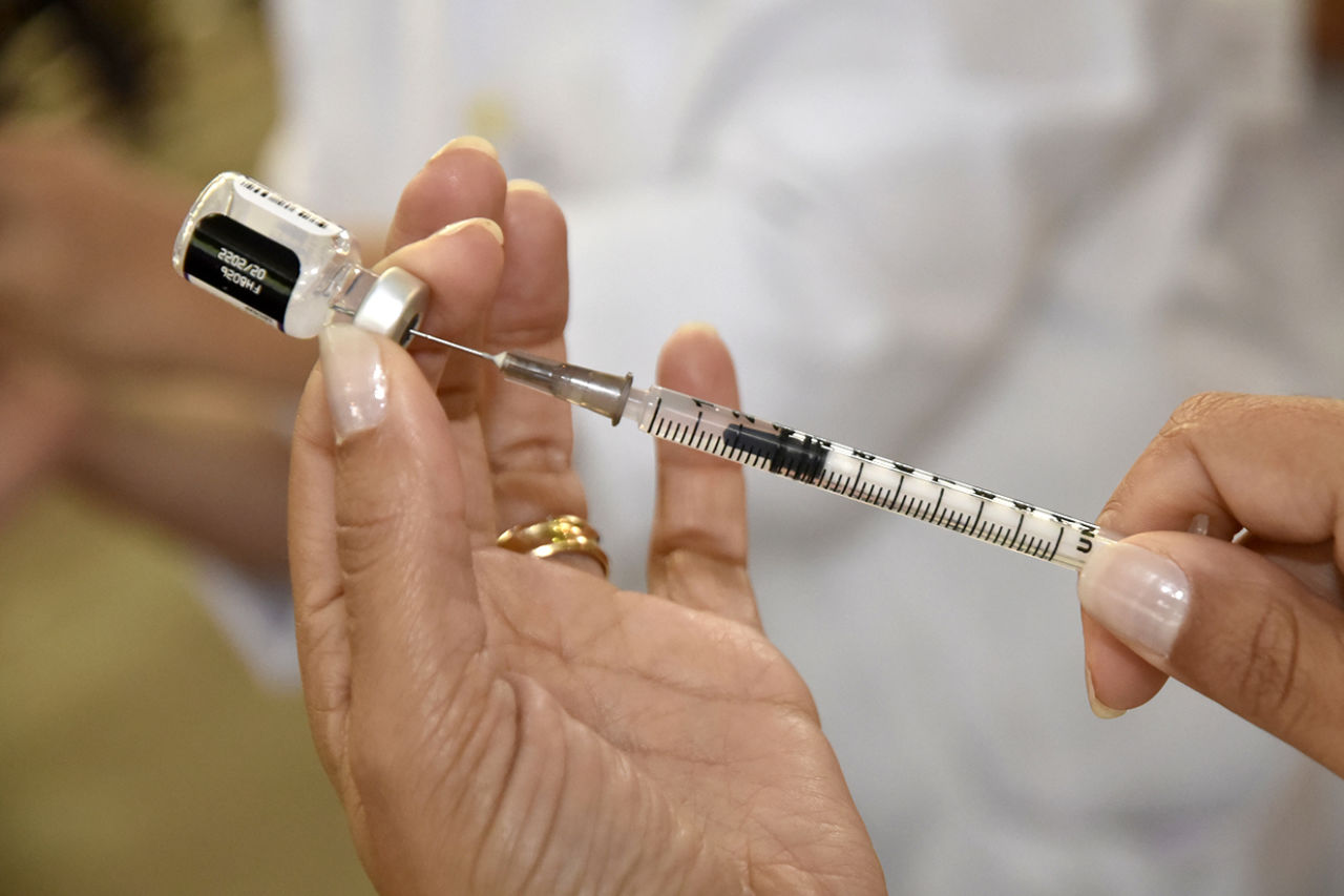 Pessoa administrando seringa de vacina