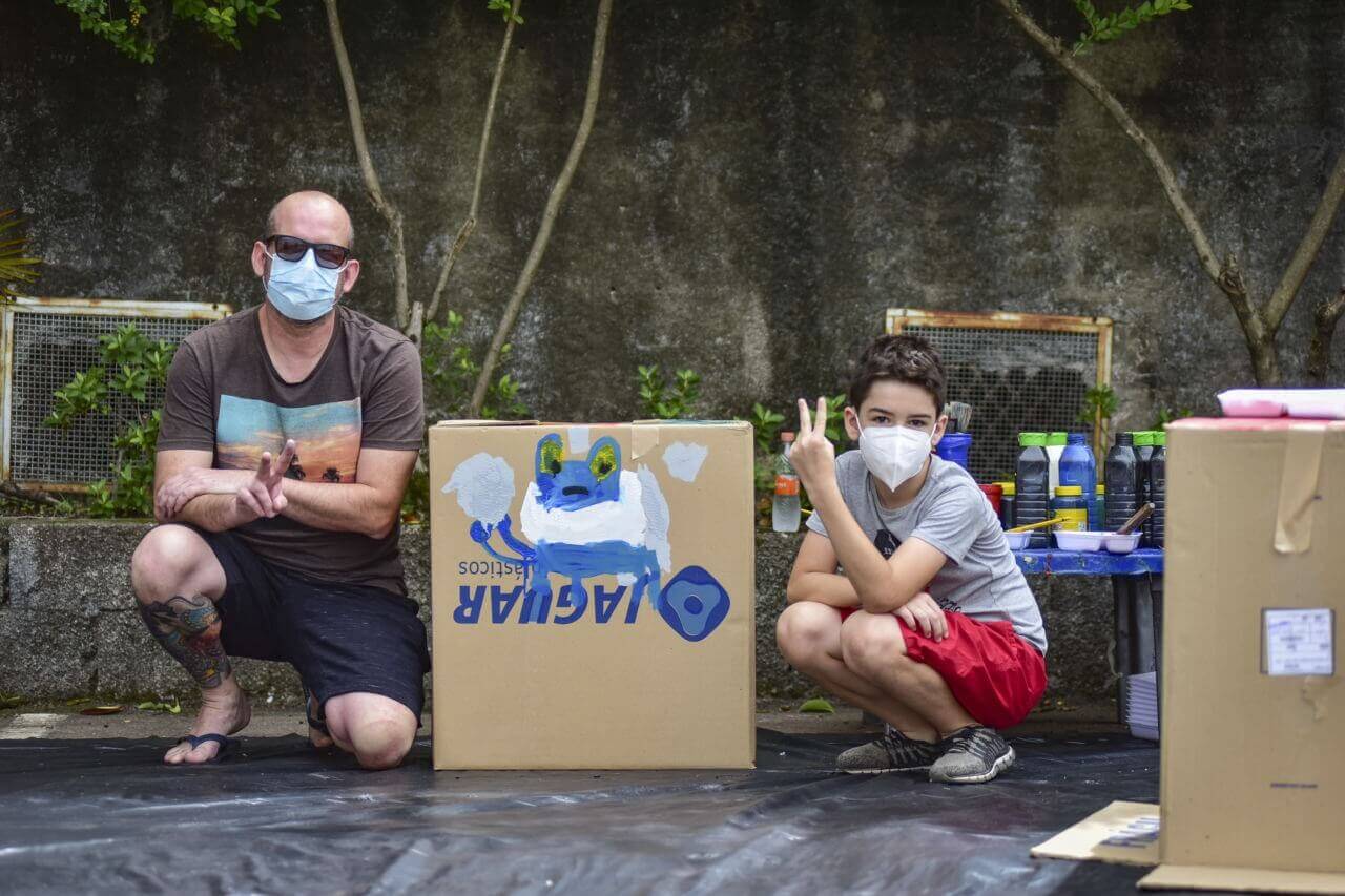 Pai e filho em frente à caixa de papelão pintada
