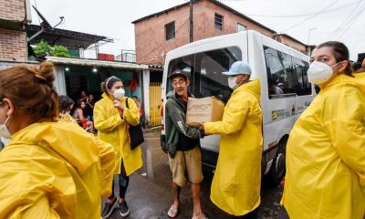 Pessoas com capas de chuva amarelas fazendo doações de alimentos