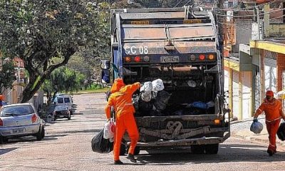 Caminhão de lixo com coletores com sacos de lixo na mão para colocar no caminhão