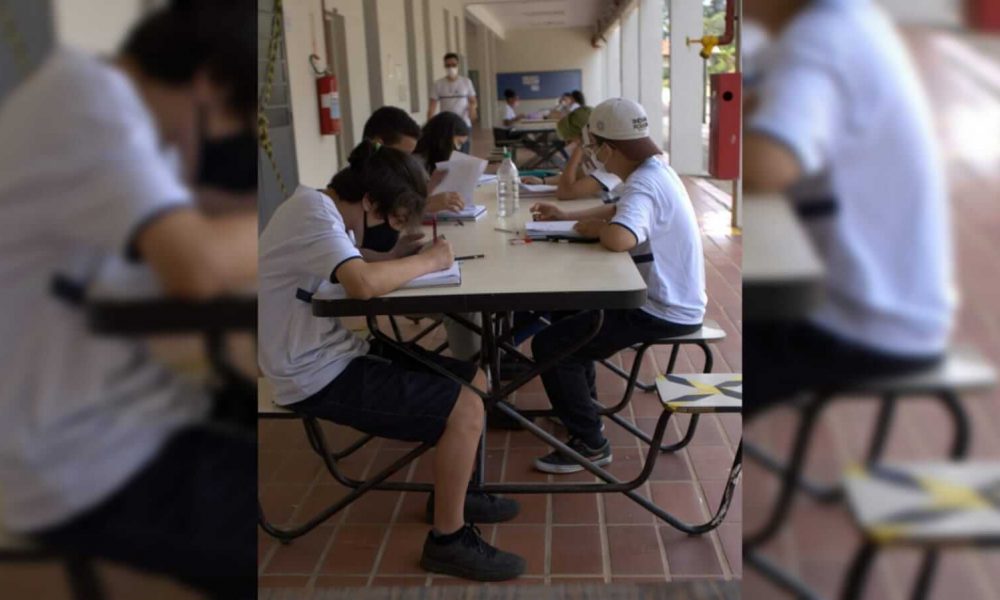 Adolescentes sentados envolta de uma mesa na escola estudando
