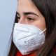 mulher jovem de cabelos castanhos usando máscara de proteção PFF2