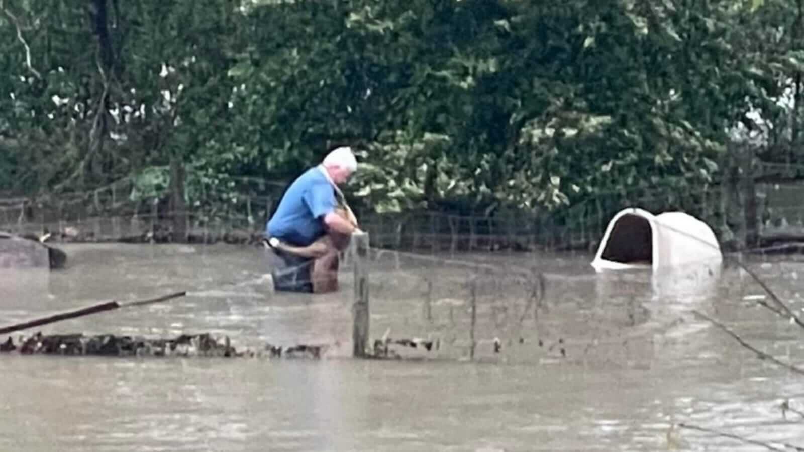 Homem abraçando cachorro em enchente