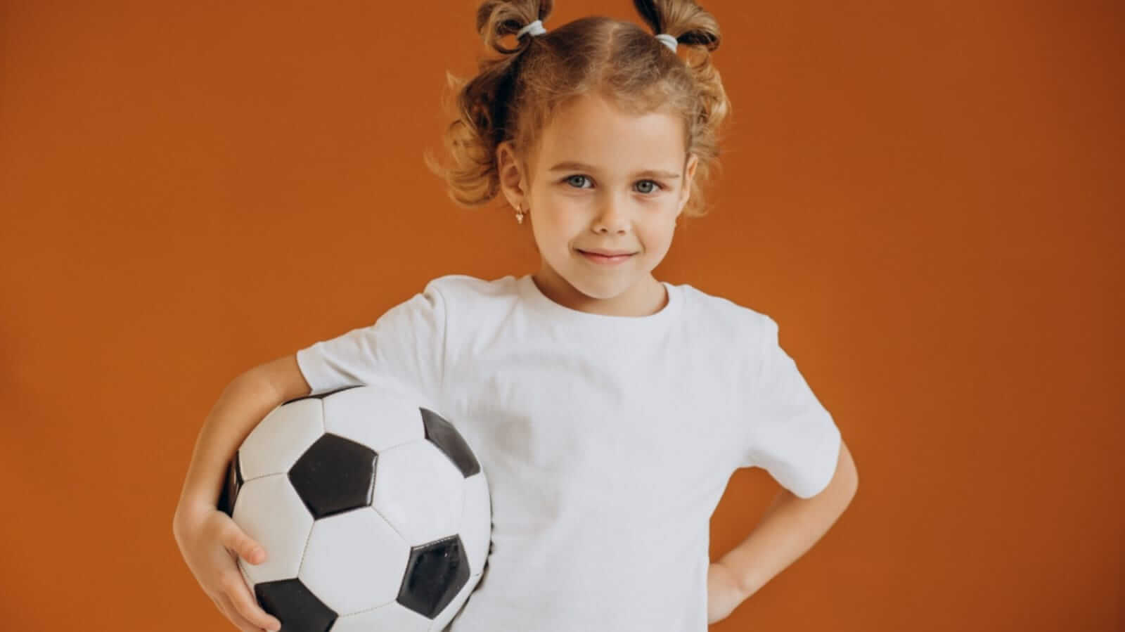 Menina segurando uma bola de futebol