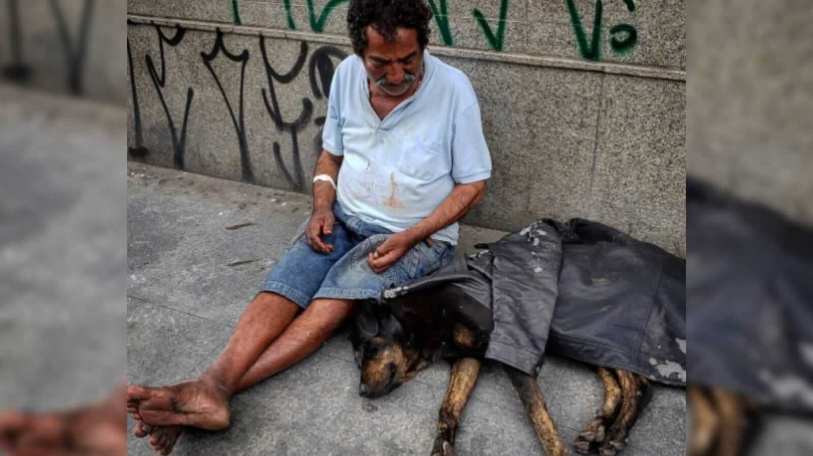Homem em situação de rua e cachorro deitado