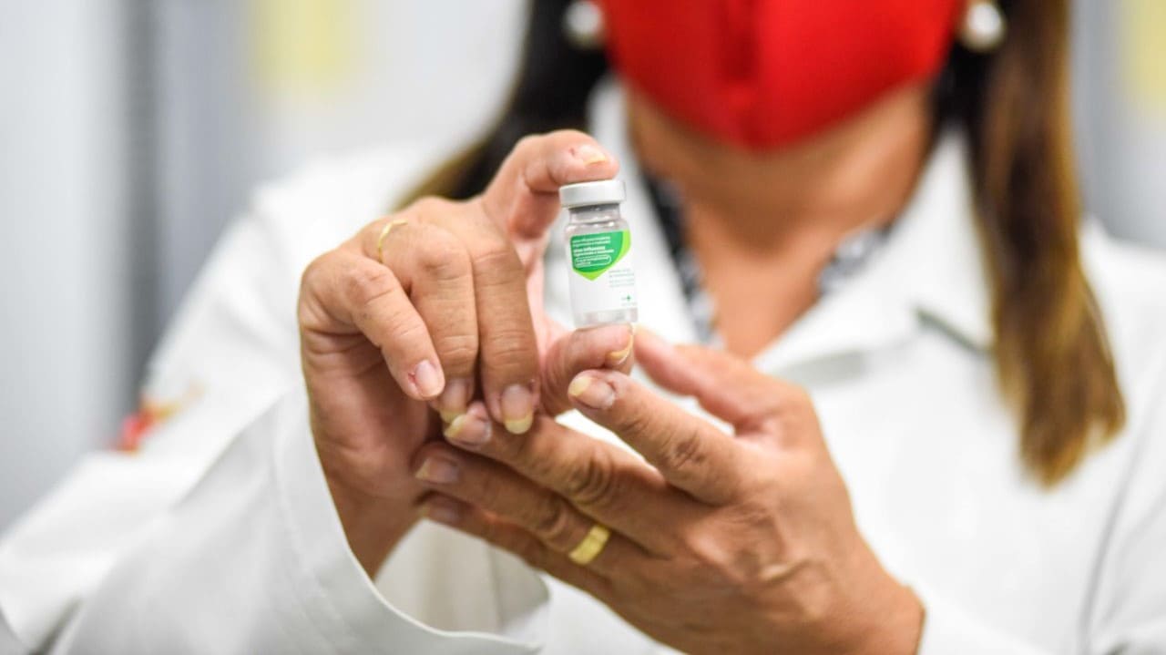 Mulher segurando ampola de vacina contra gripe