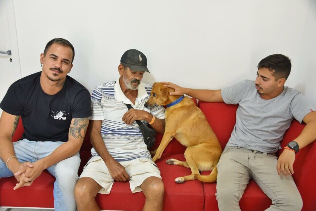 Três homens em sofá com cachorro