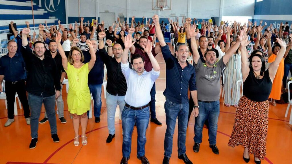 Pessoas em ginásio levantando as mãos
