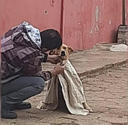 Homem agasalhando cachorro