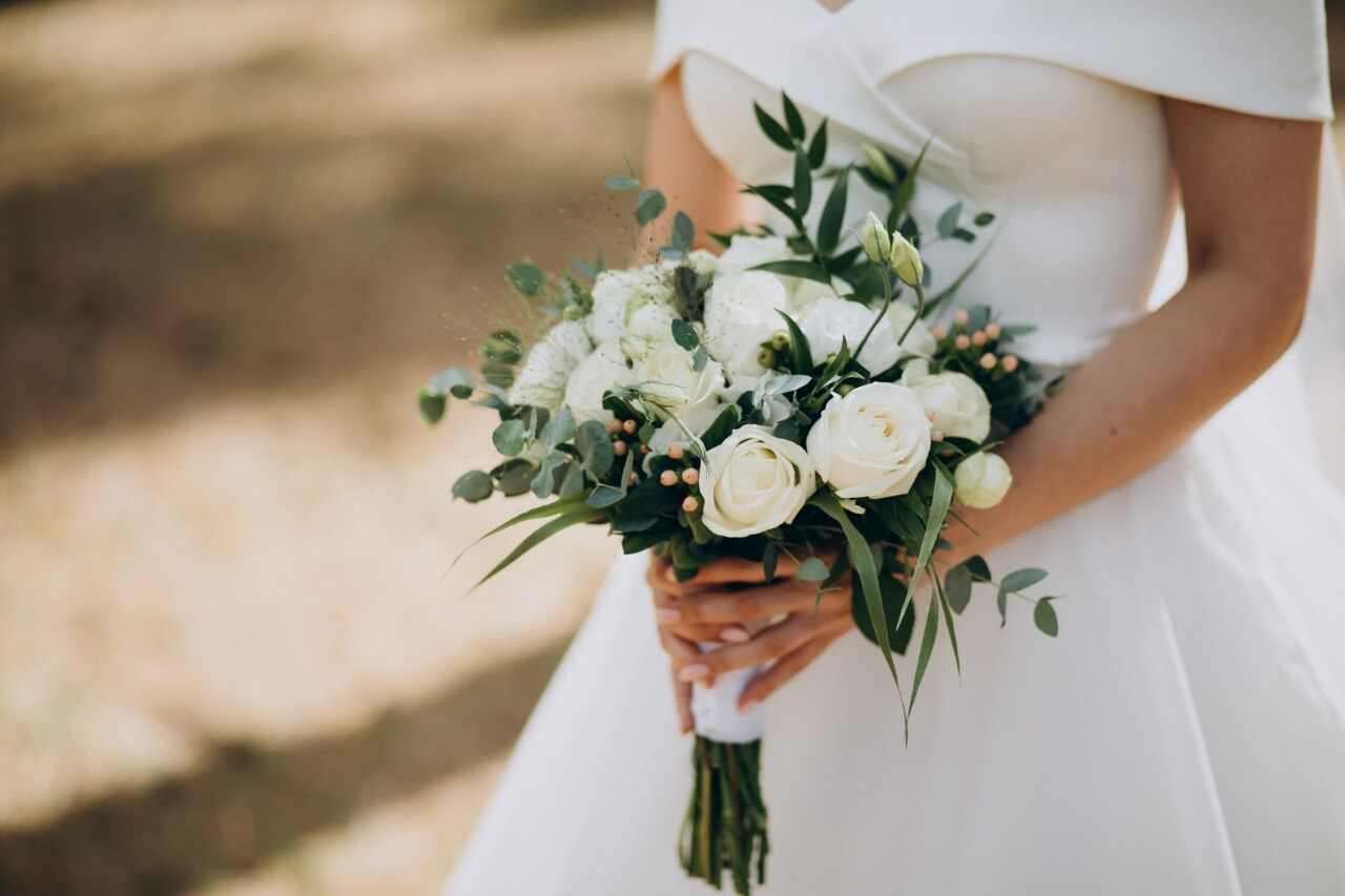 Noiva segurando um buquê de rosas brancas