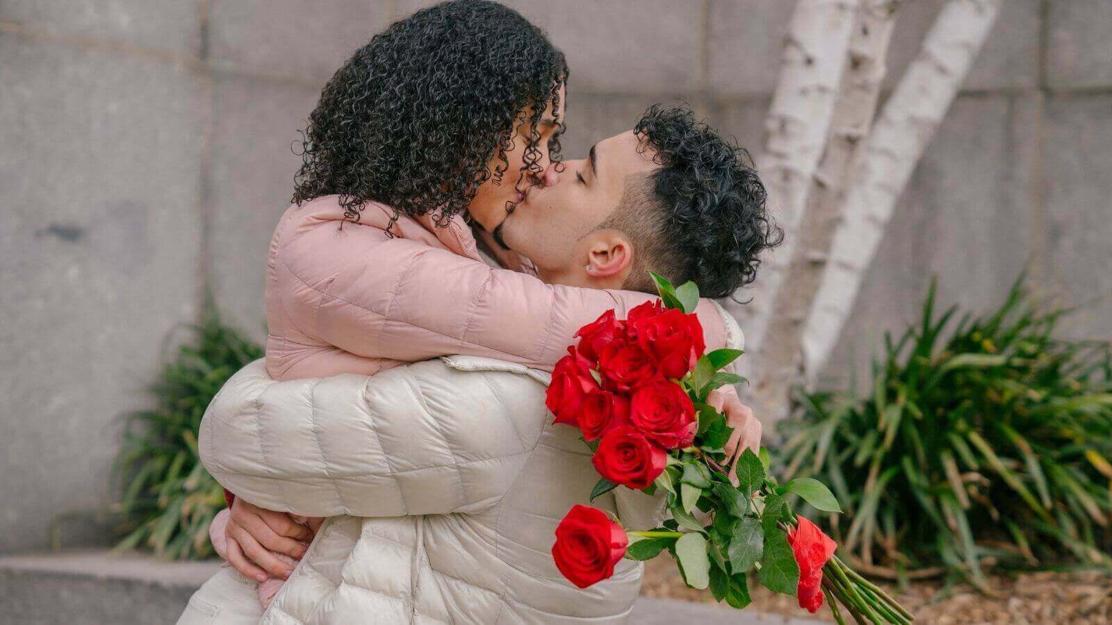Namorados se beijando com buquê de rosas