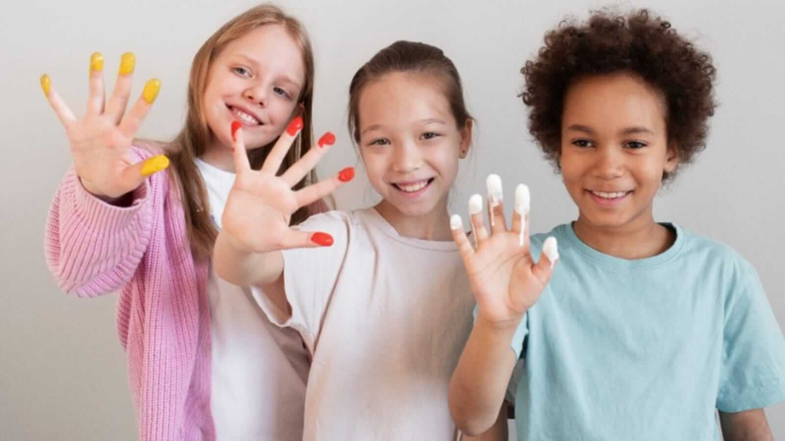 Três crianças com tinta nos dedos
