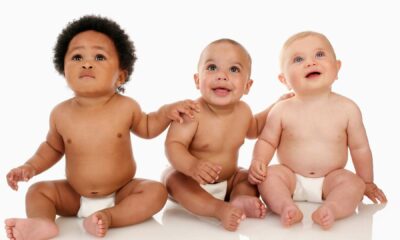 três bebês sentados rindo para foto