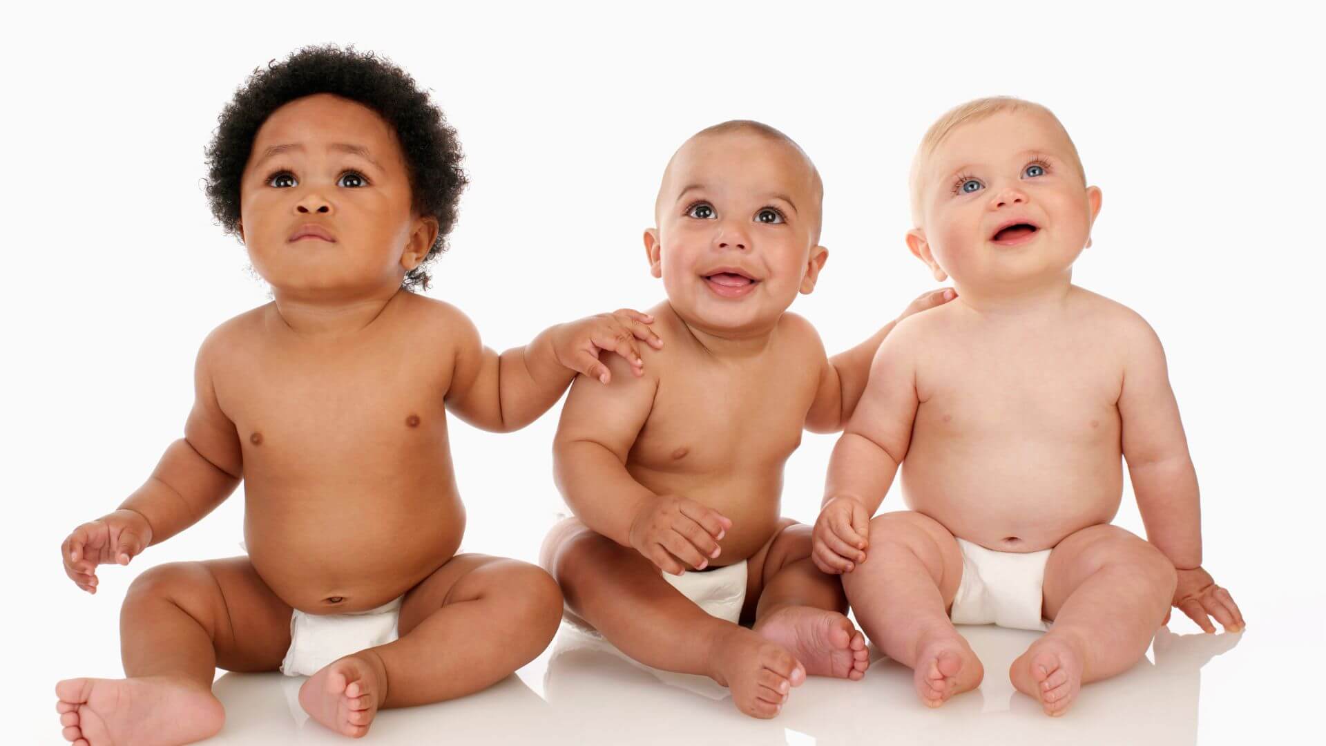três bebês sentados rindo para foto