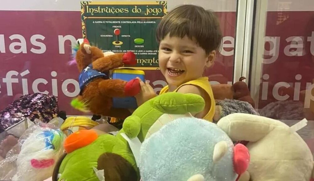 Samuel, sorrindo, dentro de máquina de bichinhos de pelúcia no Norte Shopping, na Zona Norte do Rio.