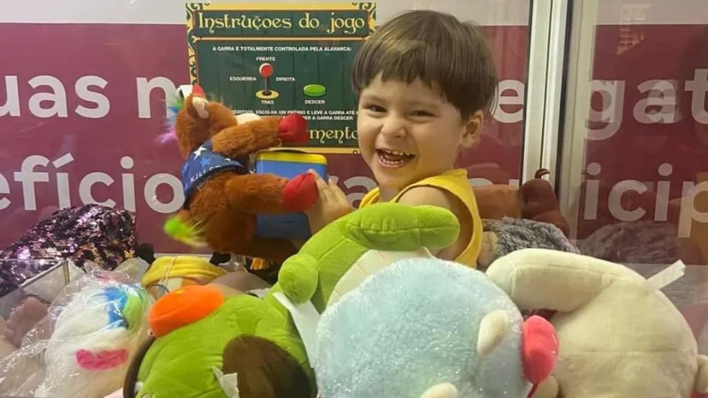 Samuel, sorrindo, dentro de máquina de bichinhos de pelúcia no Norte Shopping, na Zona Norte do Rio.