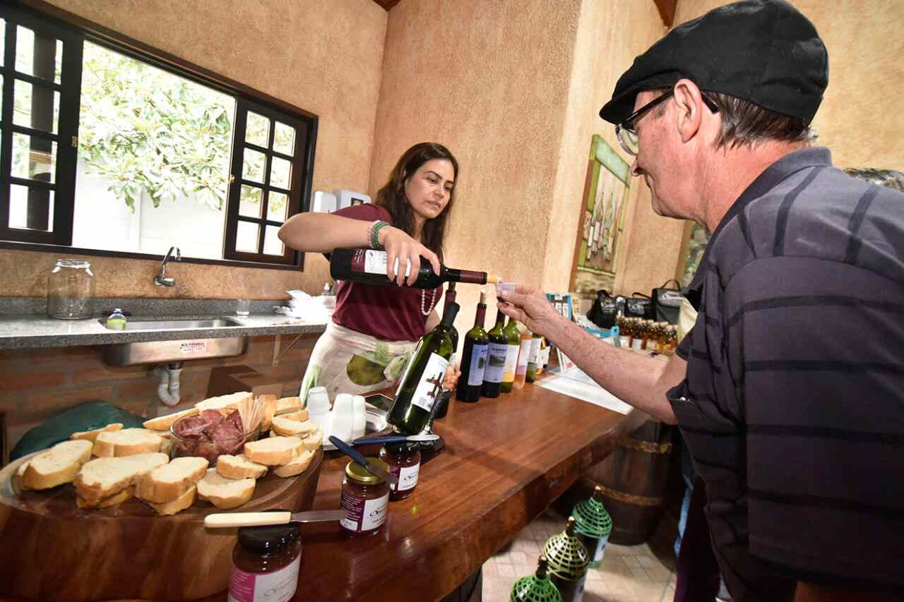 Miriam serve vinhos da Adega Oliveira para visitantes de Serra Negra