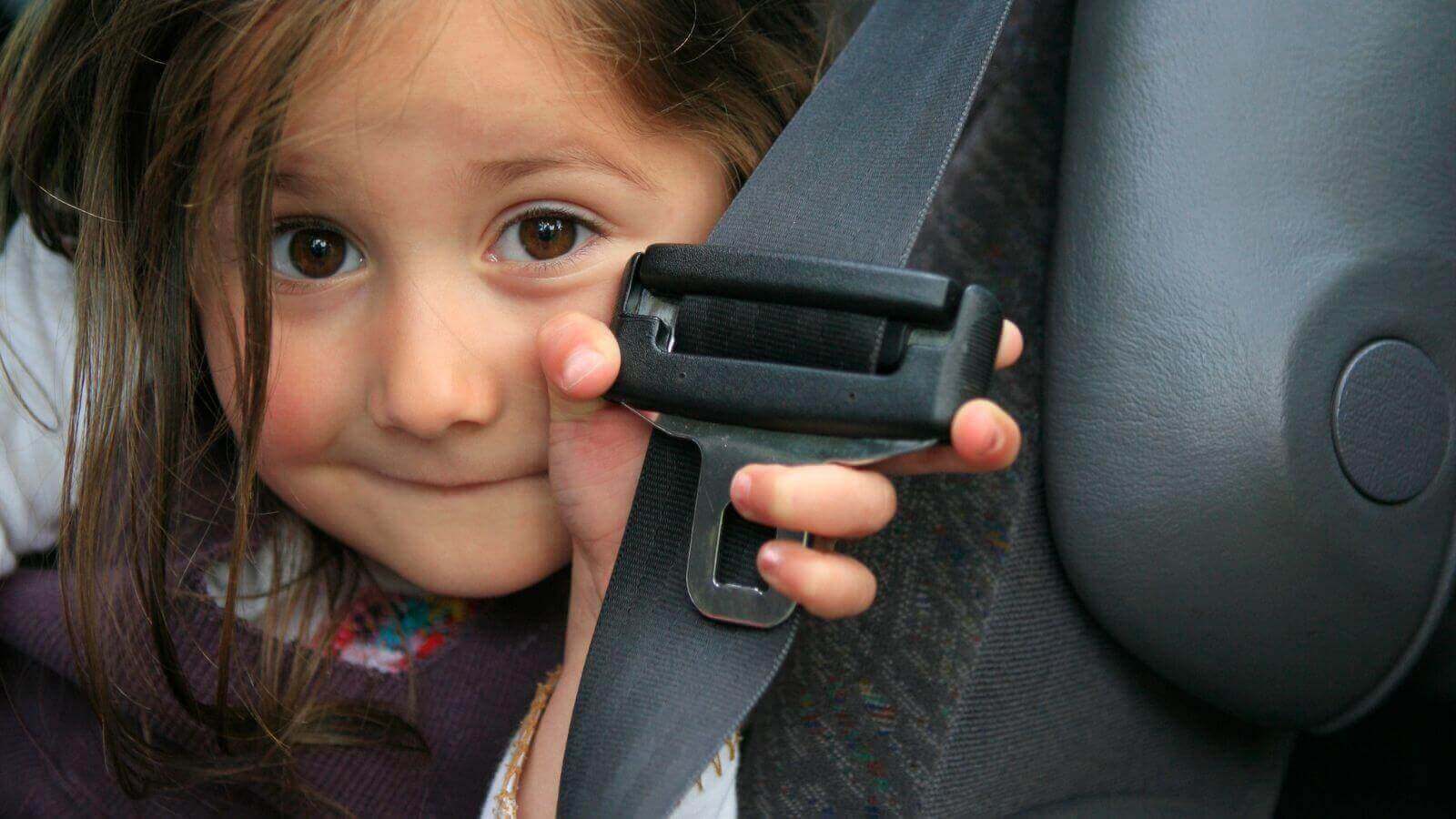 Criança com cinto de segurança na mão