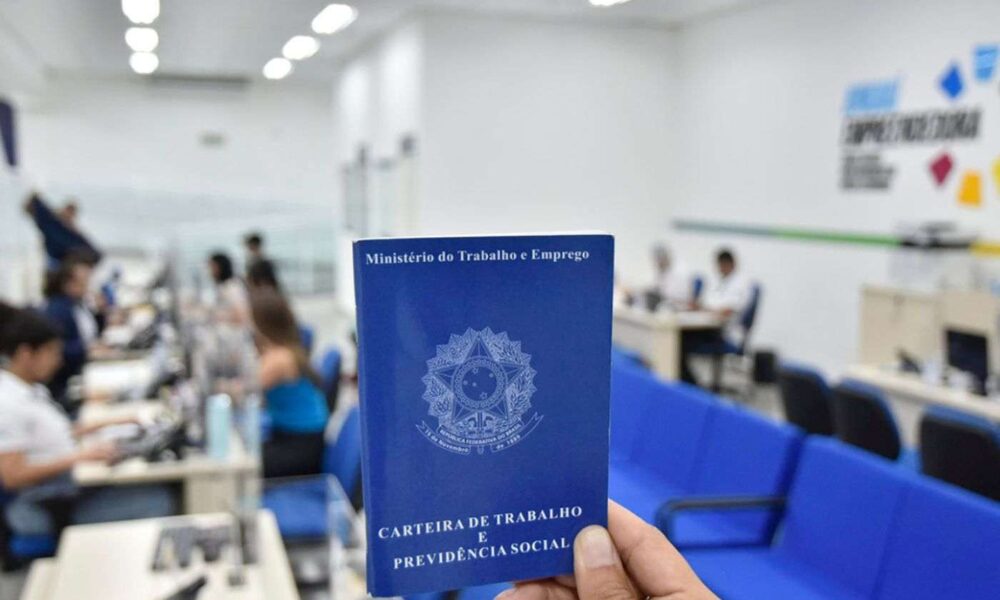 Pessoa segura carteira de trabalho em frente ao balcão do Portal Jundiaí Empreendedora, onde candidatos buscam vagas