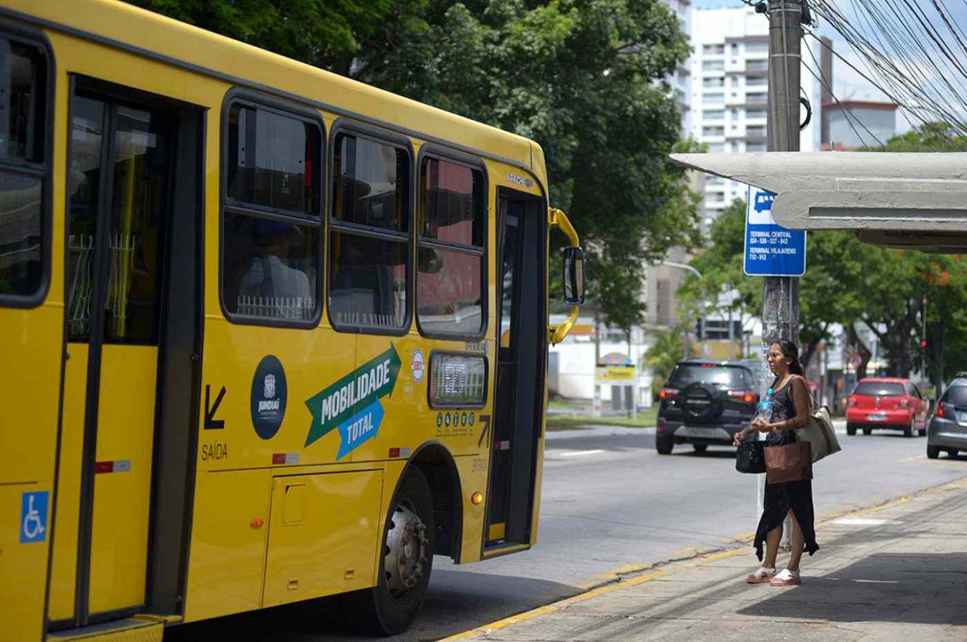Mulher em calçada e ônibus municipal de Jundiaí na rua
