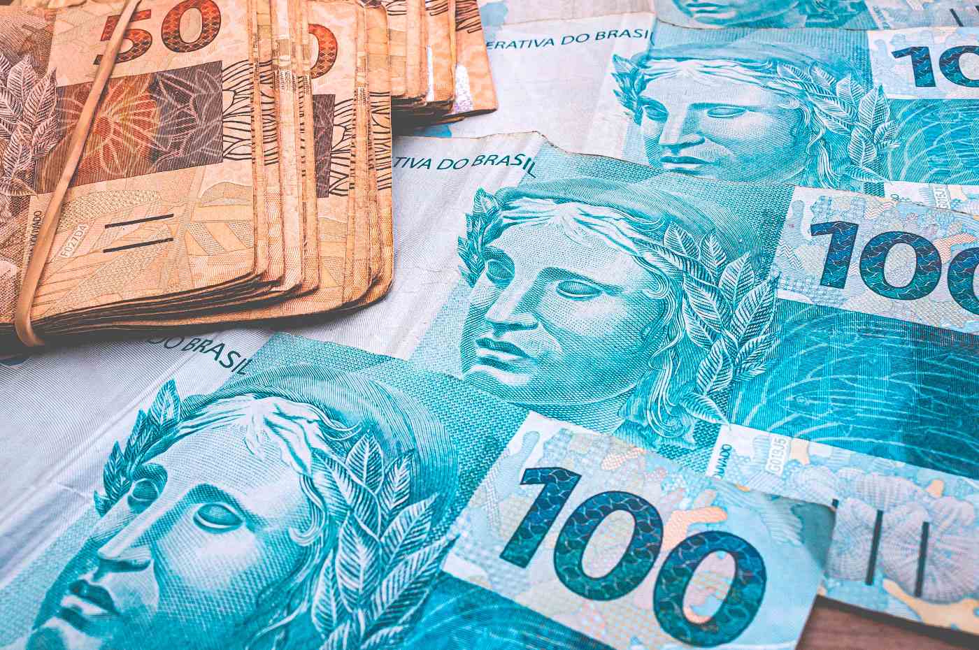 notas de dinheiro no valor de R$100,00 e R$50,00 sobre uma mesa