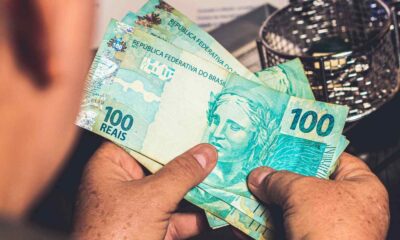 Pessoa segurando notas de R$ 100 reais brasileiros